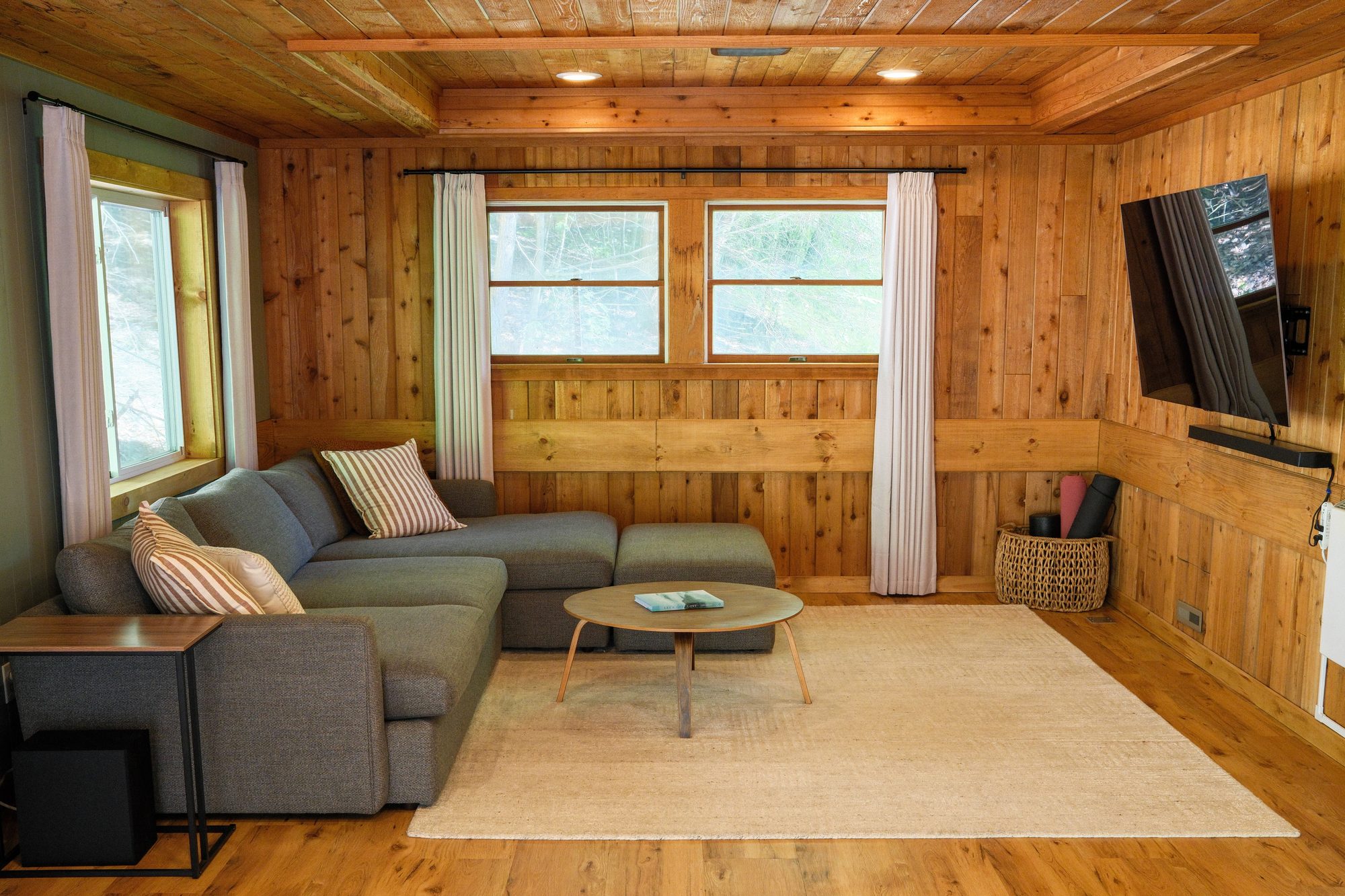 Family room with large TV, sectional couch and cedar paneling